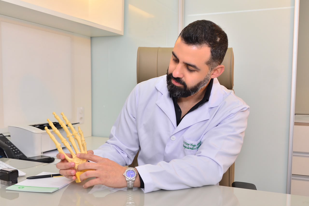 Dr. Victor Hugo analisando modelo anatômico da mão em consultório